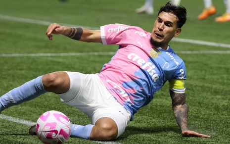 Gustavo Gómez dá um carrinho para evitar saída da bola pela linha de fundo; ele usa uniforme azul e rosa do Palmeiras