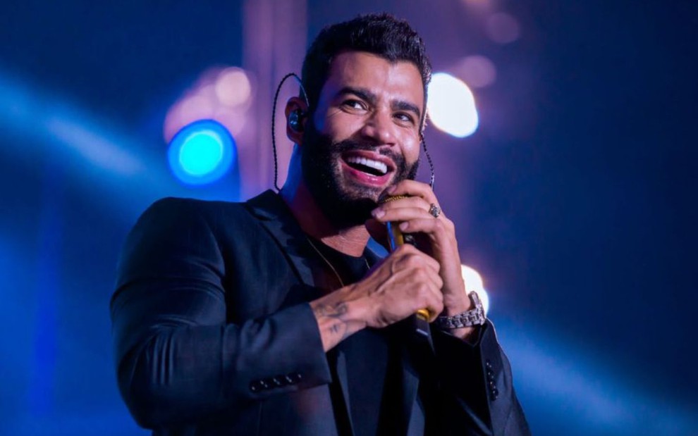 Gusttavo Lima segura um microfone e canta em seu show