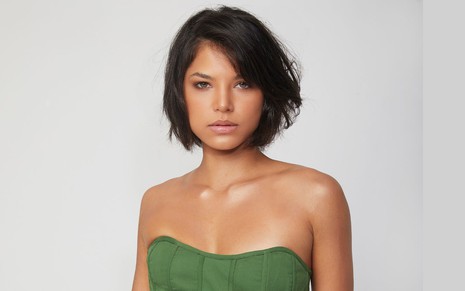 Heloísa Honein com os cabelos curtos, usando blusa verde sem manga e fazendo carão para a foto