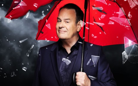 Dan Aykroyd segura um guarda-chuva vermelho enquanto pedaços de vidro caem ao seu redor