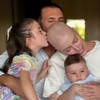 Fabiana Justus recebe beijo na careca de uma filha e do marido enquanto segura Luca e recebe abraço da outra filha