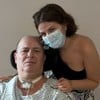 Isabella Aglio posa com o pai, o baixista Mingau, no hospital; ele usa trajes hospitalares, e ela uma máscara
