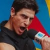 Reynaldo Gianecchini faz pose com microfone em cenário com fundo colorido