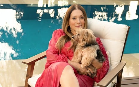 Susana Vieira posa com seu cãozinho, Bob, em uma cadeira à beira da piscina