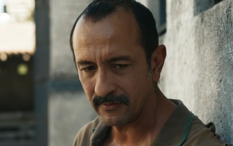 Irandhir Santos com expressão séria em cena como Tião Galinha na novela Renascer