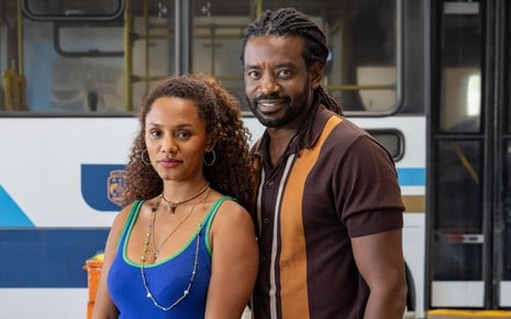 Jéssica Ellen e Fabrício Boliveira posam sorridentes em frente de um ônibus em foto de Volta por Cima