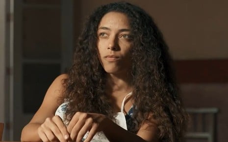 Em cena de Renascer, Alice Carvalho está olhando para alguém, com a expressão séria