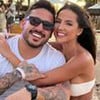 João Hadad e Luana Andrade abraçados, numa praia, sorrindo para foto