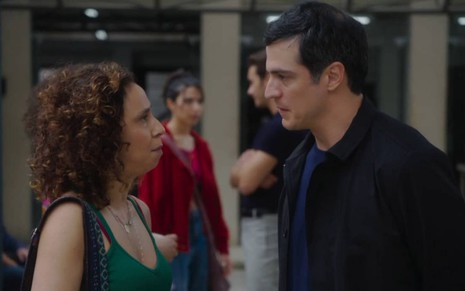 Os atores Thalita Carauta e Mateus Solano um de frente para o outro, sérios, em cena de Elas por Elas
