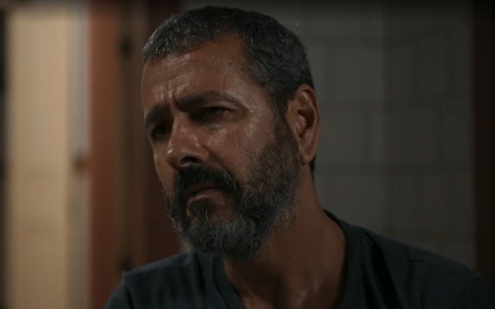 Em cena de Renascer, Marcos Palmeira está com a expressão séria; ele usa blusa cinza