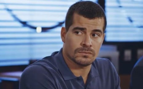 Em cena de Família É Tudo, Thiago Martins está com a expressão de tristeza; ele usa blusa azul marinho