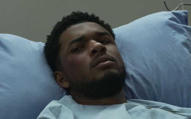 Juan Paiva está deitado em uma cama de hospital, em cena de Justiça 2