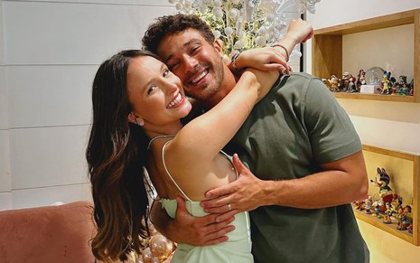 Larissa Manoela usa um vestido verde claro e abraça André Luiz Frambach. Os dois sorriem para a câmera.