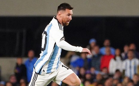 Lionel Messi correndo com a bola em jogo da Argentina nas Eliminatórias da Copa; ele usa o uniforme tradicional, azul e branco
