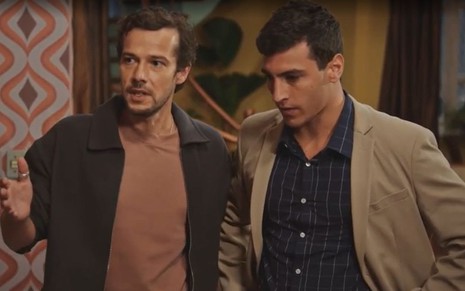 Em cena de Família É Tudo, Jayme Matarazzo está falando com alguém, com a expressão séria, e Henrique Barreira está ao lado