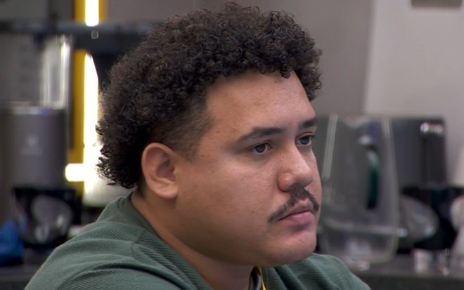 Lucas Henrique Ferreira com expressão séria na cozinha do BBB 24