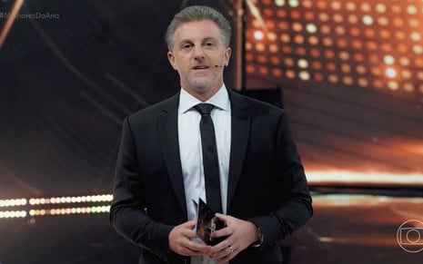 De terno e gravata, Luciano Huck está no palco do Melhores do Ano 2023