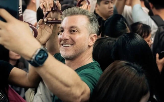 Luciano Huck tirando foto dentro de metrô lotado na cidade de Guangzhou, na China