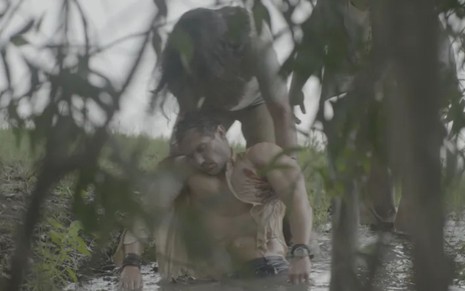 Raoni (Mapu Huni Kui) puxa Vinícius (Paulo Rocha) de rio em cena da novela Terra e Paixão