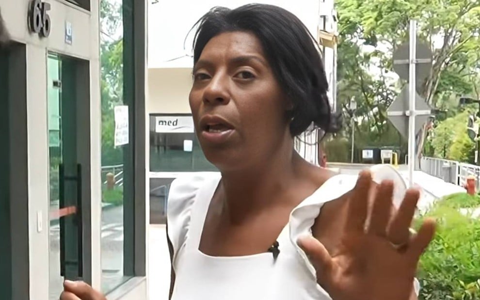 Foto de Márcia Fu durante entrevista; ela está com o cabelo solto e veste vestido branco