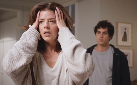 Natália (Mariana Santos) está com as mãos na cabeça, e Bruno (Luan Argollo) aparece atrás dela em cena de Elas por Elas