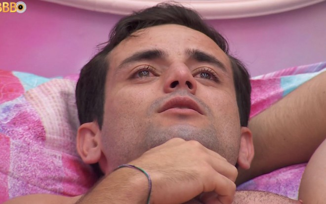 Matteus Amaral está deitado na cama, no BBB 24, e chora