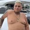 MC Ryan está sem camisa e se apoia em um iate