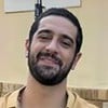 Miguel Rômulo usa camisa xadrez amarela e posa com os braços cruzados e sorrindo nos bastidores de Renascer