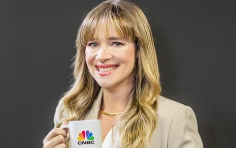 Natália Ariede sorri e segura uma caneca com o logo da CNBC