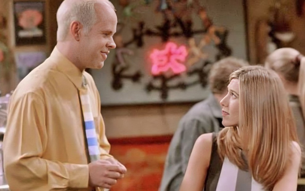 James Michael Tyler olha sorridente para Jennifer Aniston em cena de Friends