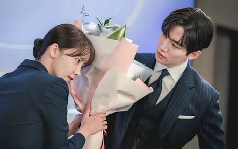YoonA se esconde atrás de um buquê de flores, enquanto Junho tenta vê-la em foto de Sorriso Real