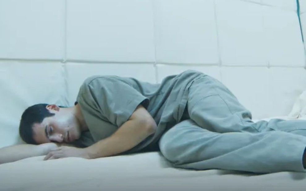 Nicolas Prattes deitado no chão em cena da novela Todas as Flores