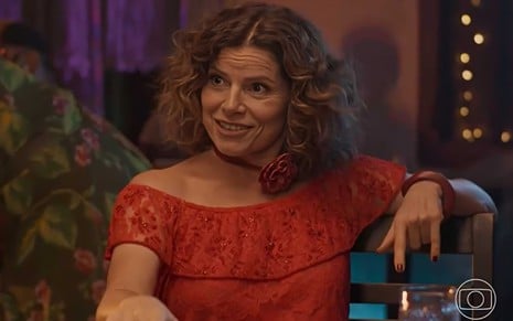 A atriz Debora Bloch de vestido vermelho, com expressão surpresa em cena de No Rancho Fundo