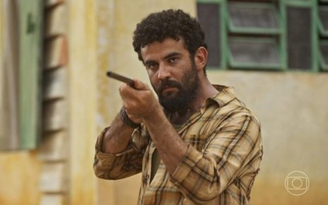 O ator Igor Fortunato com espingarda em mãos em cena de No Rancho Fundo