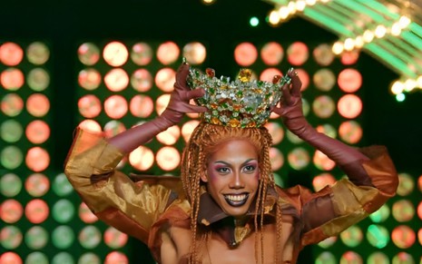A drag queen Organzza colocando uma coroa verde e amarela na cabeça na final de Drag Race Brasil