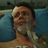 Pablo Sanábio está deitado em maca bastante machucado e usa oxigênio em cena da série Sob Pressão