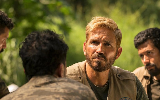 Com cabelo tingido de loiro e olhar distante, Jim Caviezel está no meio de uma selva em cena de Som da Liberdade