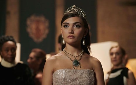 Daniela Nieves tem expressão altiva em cena de Academia de Vampiros; ela usa um vestido longo, um colar de joias e uma tiara