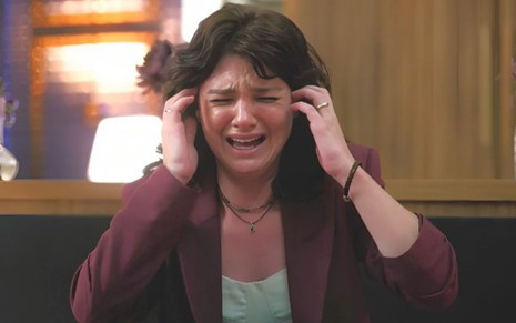 Debora Ozório com expressão de choro e colocando as mãos na cabeça em cena como Petra na novela Terra e Paixão