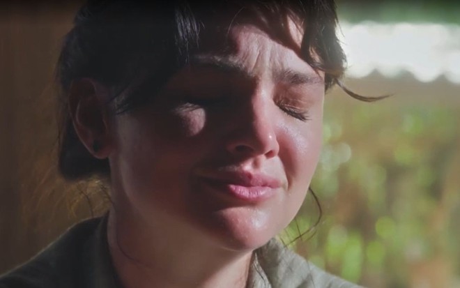 Em cena de Terra e Paixão, Debora Ozório está chorando, com os olhos fechados