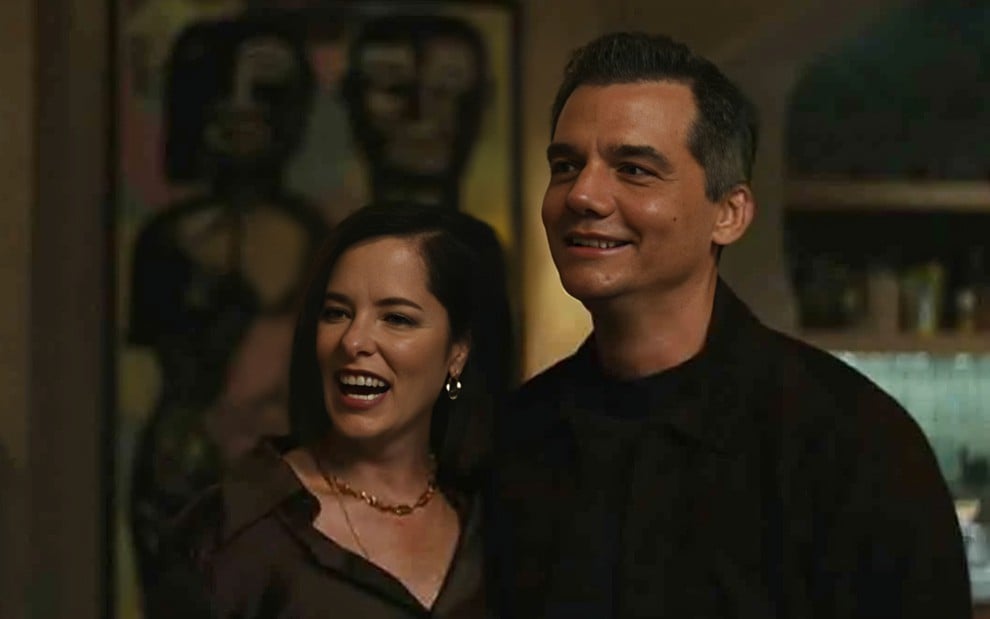 Parker Posey e Wagner Moura estão abraçados e sorriem em cena da série Sr. e Sra. Smith