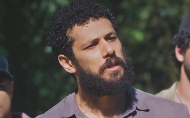 Em cena de Terra e Paixão, Amaury Lorenzo está falando com alguém com a expressão de tensão