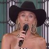 Com chapéu de caubói e blusa branca com bolas de metal, Adriane Galisteu apresenta A Fazenda 15