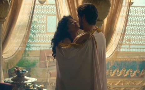 Ingrid Conte como Naamá com Guilherme Dellorto como Salomão enrolados em um lençol em um aposento privado em cena de Reis