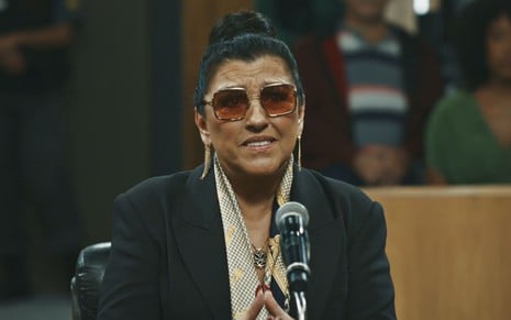 Regina Casé usa óculos escuros no tribunal e está com expressão séria em cena como Zoé na novela Todas as Flores