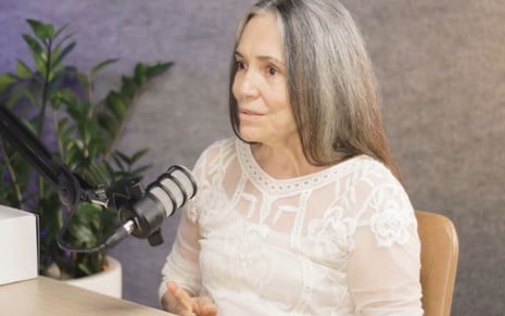 A atriz Regina Duarte de cabelo grisalho e blusa branca em entrevista a um podcast