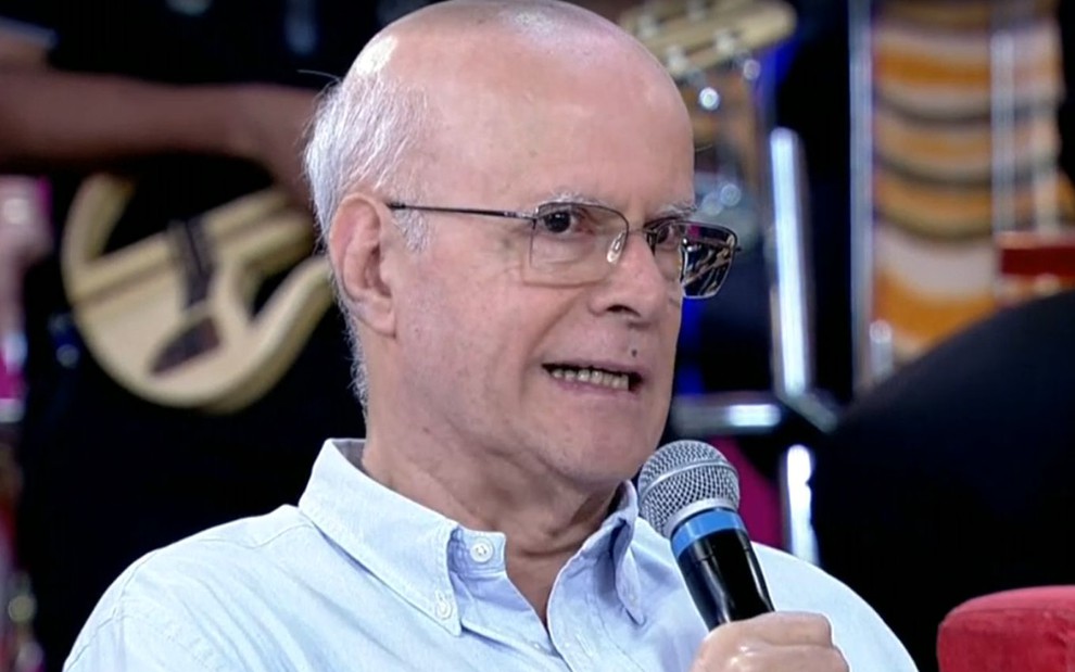 Reinaldo Pimenta com microfone na mão e óculos