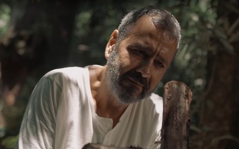 Em cena de Renascer, Marcos Palmeira está chorando em frente à uma cruz