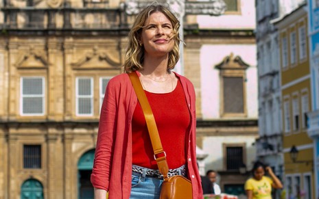 De casaquinho e blusa vermelha, calça jeans e bolsa caramelo, Rita Lobo posa no Pelourinho, em Salvador, na Bahia