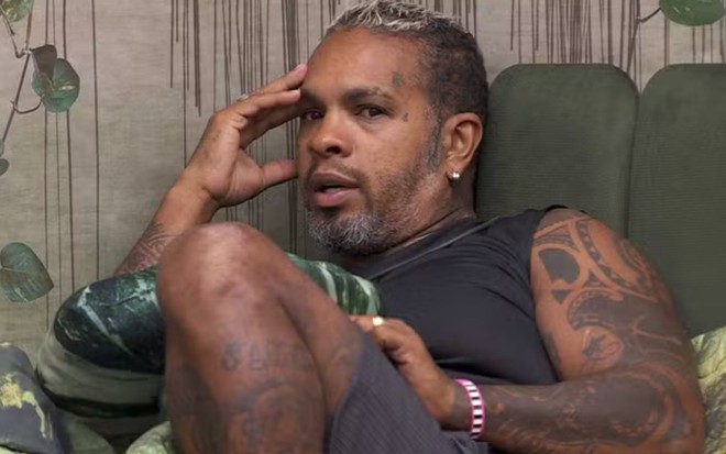 Rodriguinho sentado na cama do quarto gnomo do BBB 24